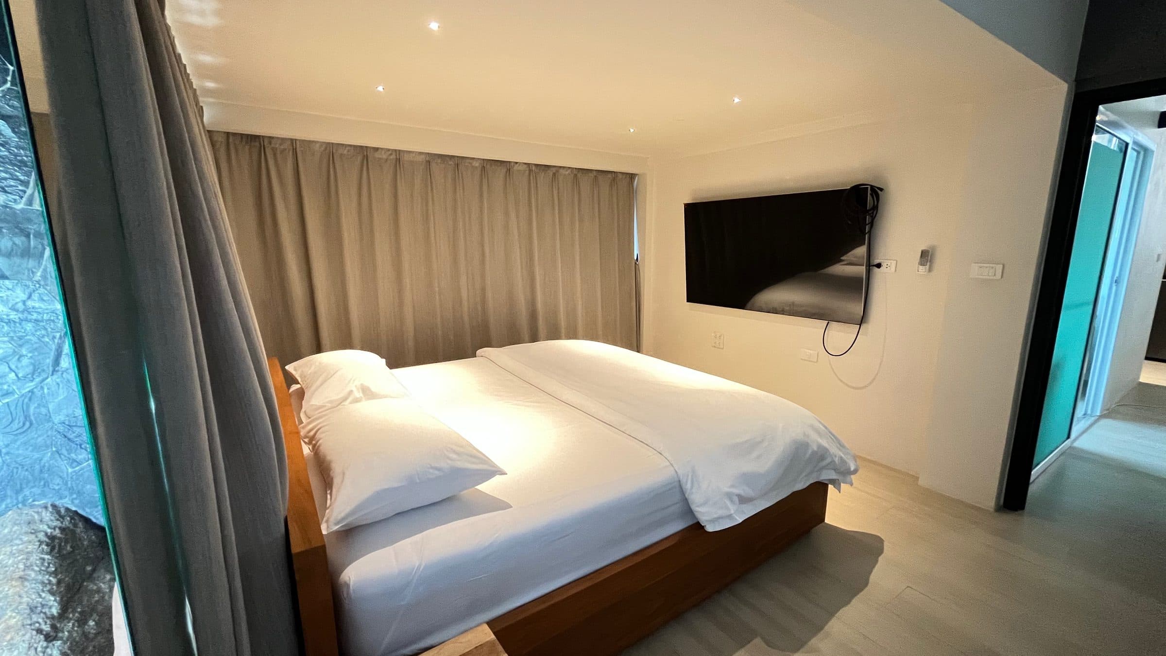 Bedroom with wall TV and natural rock by the window