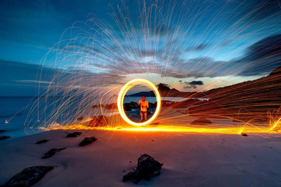 Fire show sparks spinning on the beach at night
