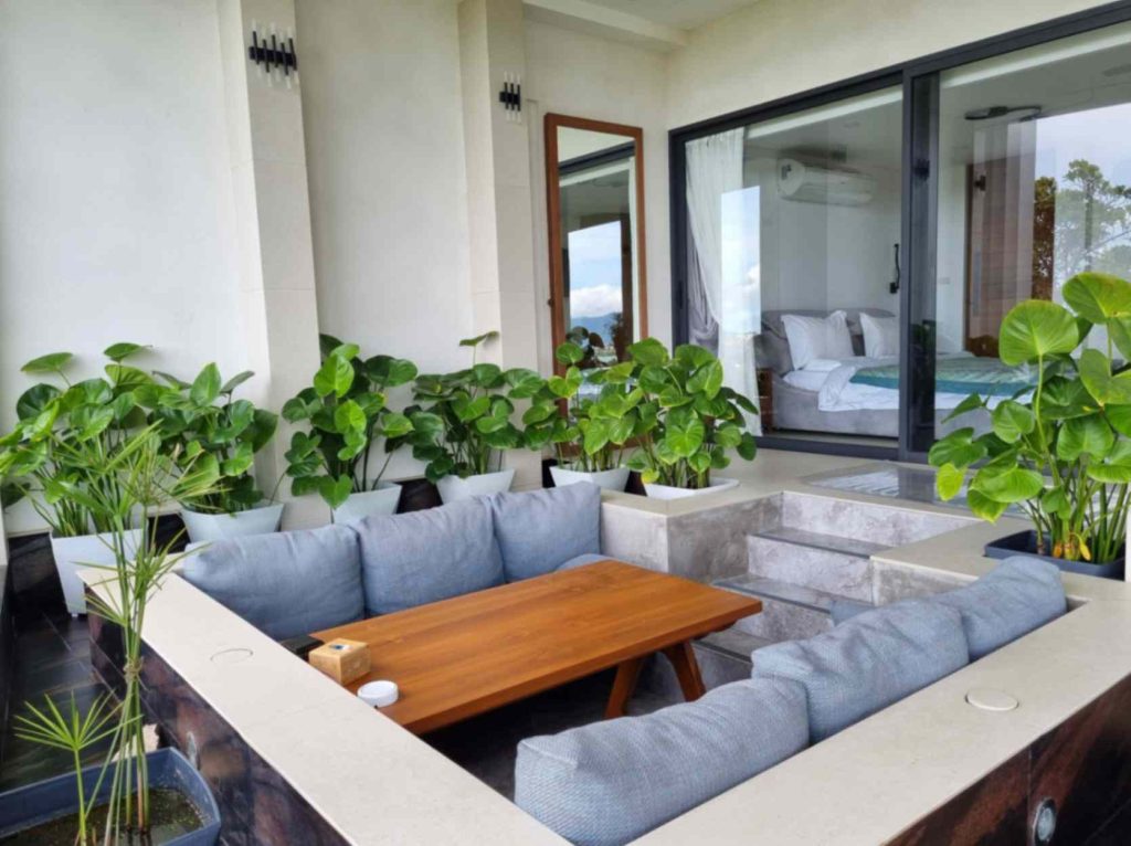 View of the comfortable lounging area of the Garden Suite, complete with potted plants and a wooden table.