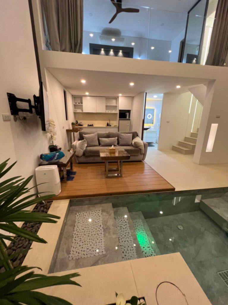 Spacious living room with high ceilings, comfortable seating, and an indoor pool in the Sunrise Suite.