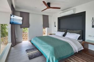 Modern bedroom in Magic Suites featuring a large bed with teal covers, wooden flooring, and ambient lighting.