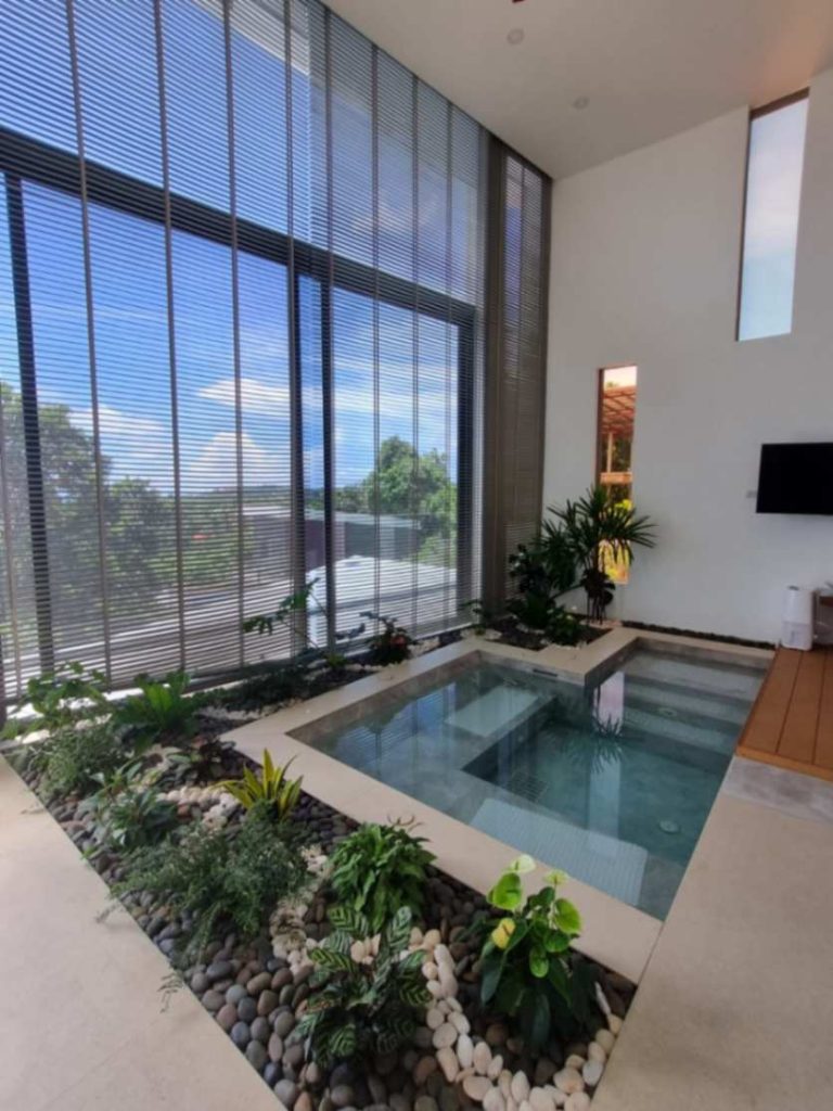 Luxurious eco-friendly Sunrise Suite villa interior featuring a small indoor pool surrounded by a lush garden.