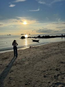 Serene beach sunset with a solo traveler capturing the moment in Koh Samui.