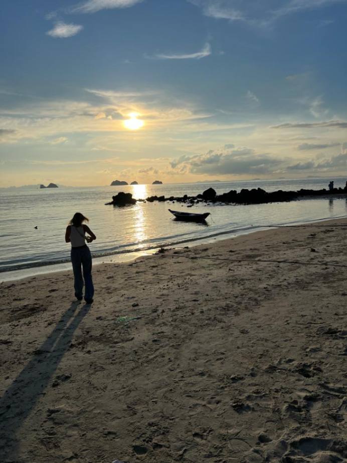 Serene beach sunset with a solo traveler capturing the moment in Koh Samui.