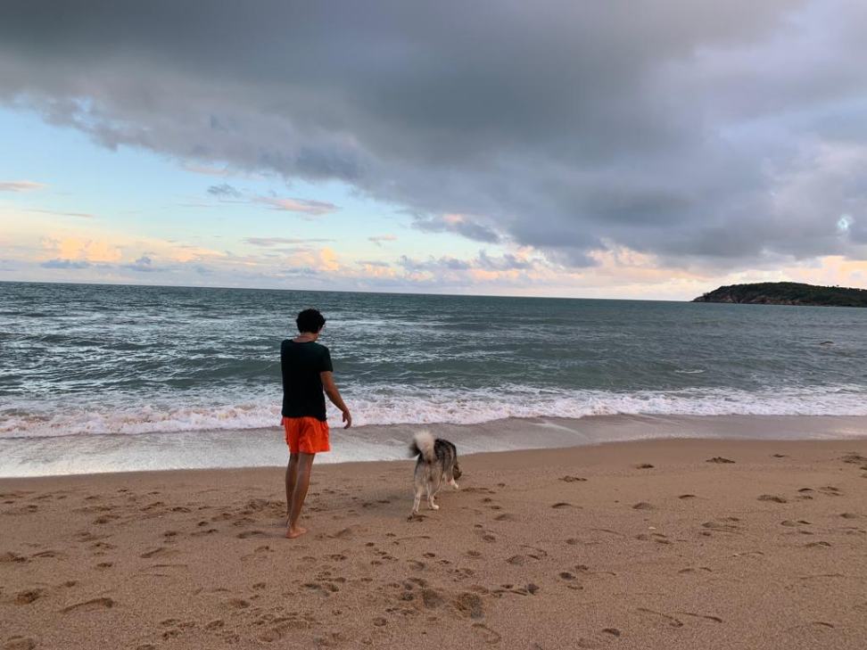 Solo traveler with his pet dog on the beach in Koh Samui.