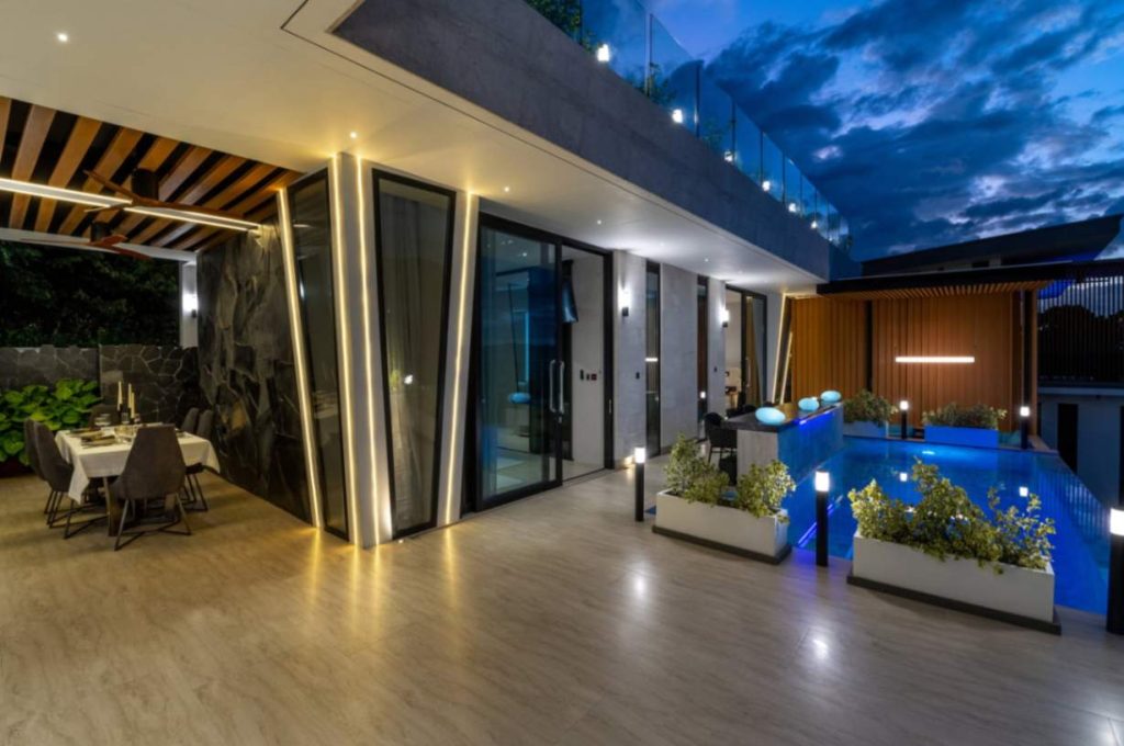 Romantic ambience in the Tuxedo villa, featuring a dining table and well-lit pool area.