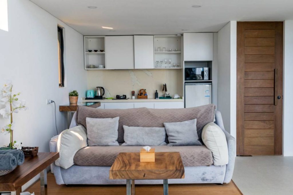 Cozy living space in Magic Suites villa with modern sofa, wooden accents, and integrated kitchen.