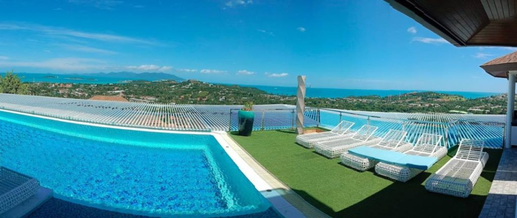 Panoramic pool view at a Koh Samui villa, with sun loungers and clear skies.