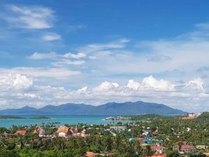 Panoramic view of Koh Samui coastline with vibrant greenery and distant mountains.