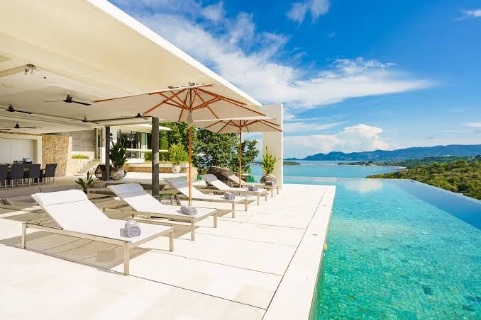 Infinity pool at a Koh Samui villa with ocean view and relaxing sunbeds.