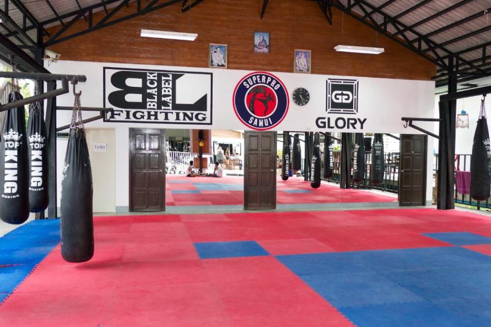 The boxing gym at Chaweng's acclaimed Superpro Samui, with training mats and boxing bags visible.
