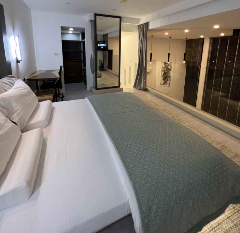 Modern Sunrise Suite bedroom featuring a comfy bed and mirror.