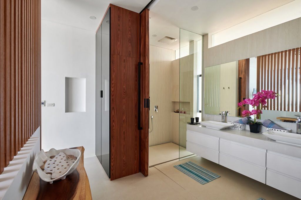Elegant bathroom in Koh Samui villa with modern design, wooden accents, and vibrant orchids.